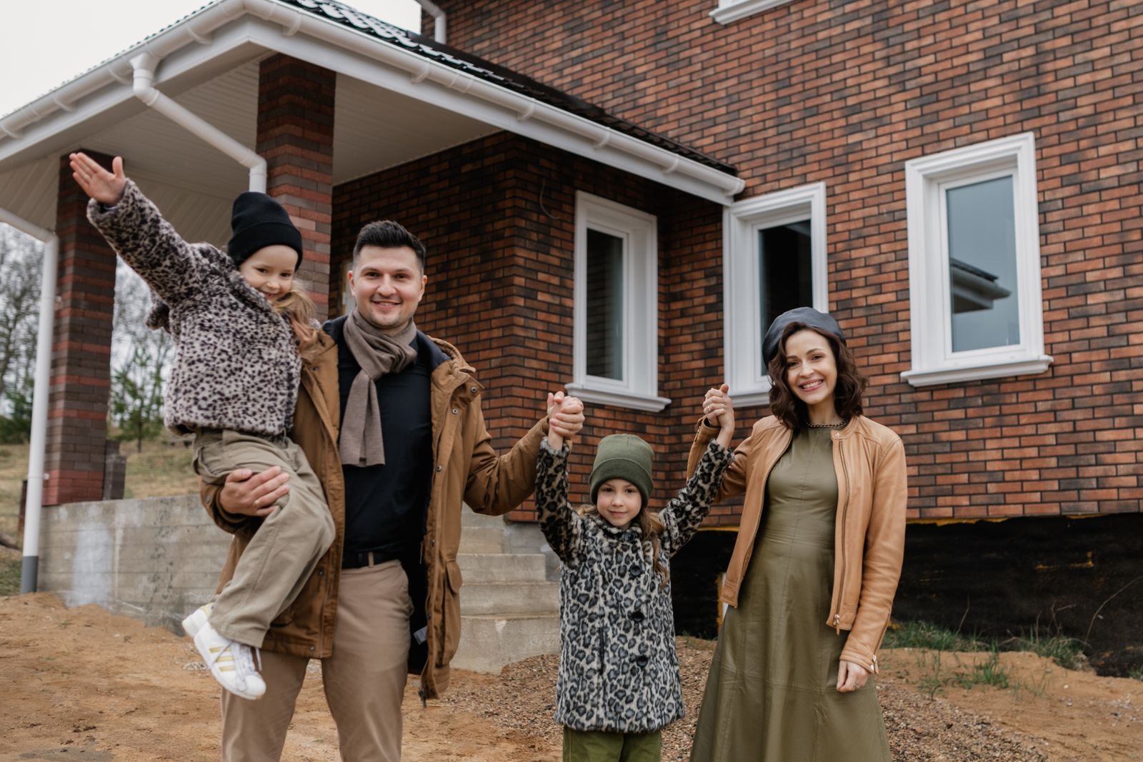 A family in front of their brand-new home on a freshly prepared lot